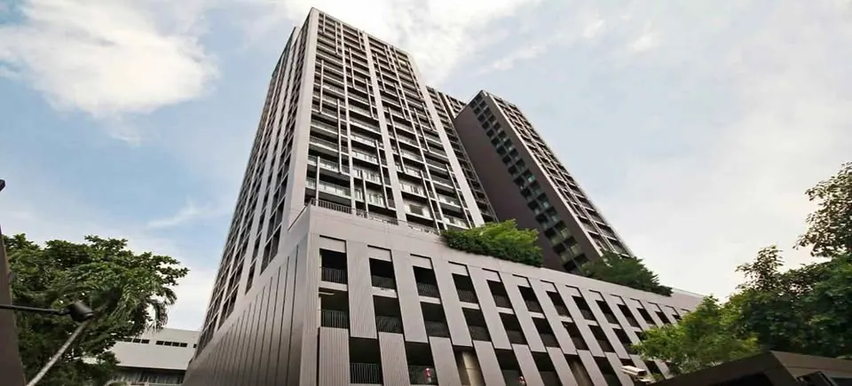 Noble Reveal Ekamai tower seen from the street below, framed by trees, unit DA-3103248