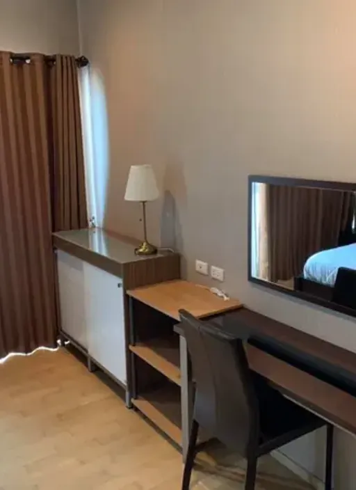 Desk with a mirror and table lamp beside a window with brown curtains, unit DA-6885